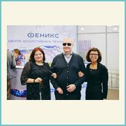 Групповая фотография организаторов фестиваля «ПРО-Зрение» в выставочном пространстве. В центре — мужчина с тёмными очками, по обе стороны от него — две женщины. Все участники стоят рядом, держа друг друга под руку.